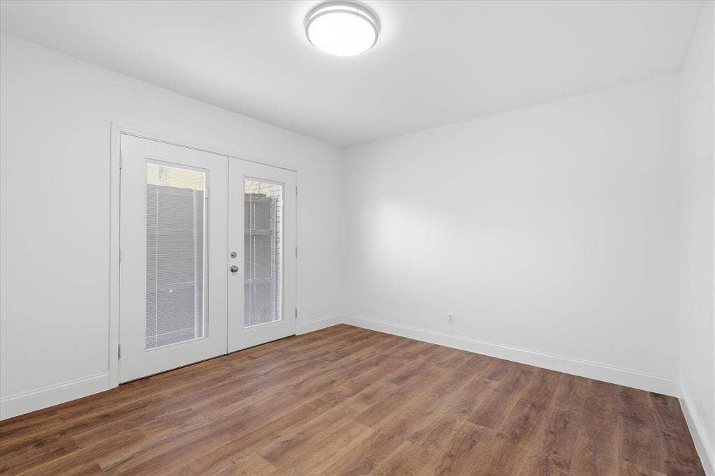 10207 Regal Oaks Drive, #109, Dallas, TX 75230 Secondary bedroom with updated flooring, fresh paint and French doors opening to a private patio area is perfect for guests, an office, study, craft or workout space with walk in closet.