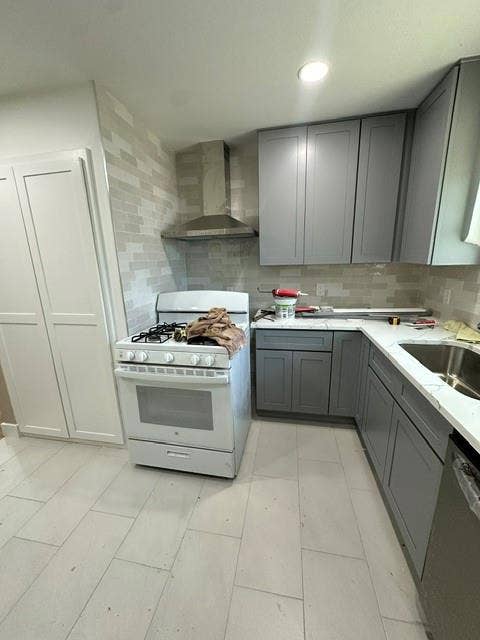 12203 Galva Drive, Dallas, TX 75243 Modern kitchen featuring stainless steel gas range and hood ventilation, soft-close cabinetry with gray finish, quartz countertops, subway tile backsplash, and tile flooring throughout