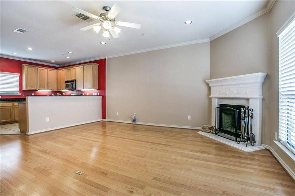 2415 Stutz Drive, #D, Dallas, TX 75235 Wood-finish flooring throughout, featuring a corner fireplace with a decorative mantel and hearth