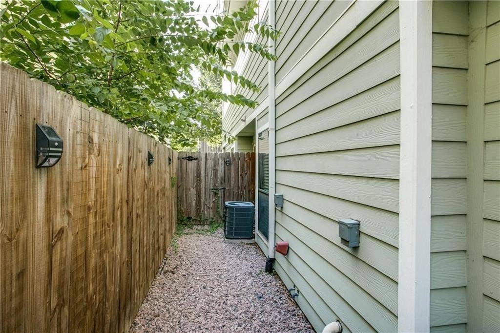 2415 Stutz Drive, #D, Dallas, TX 75235 Wood privacy fence with solar-powered wall lights, horizontal siding exterior, and a gravel pathway