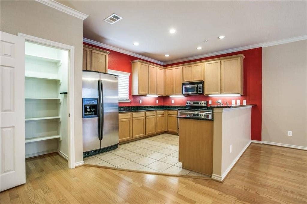 2415 Stutz Drive, #D, Dallas, TX 75235 Kitchen featuring wood cabinetry, stainless steel appliances, dark countertops, and tile flooring