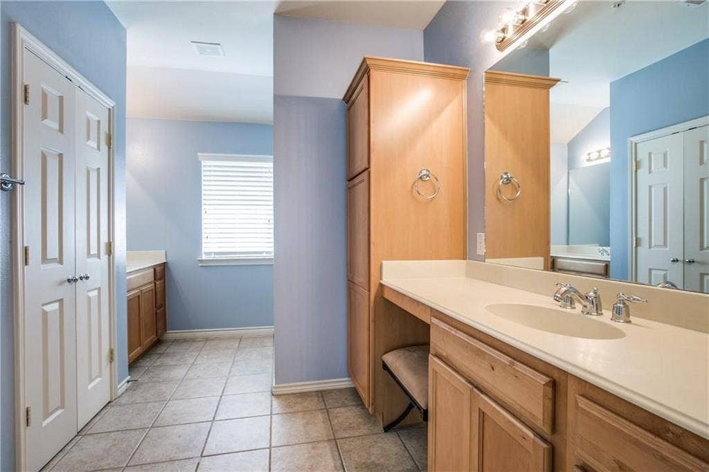2415 Stutz Drive, #D, Dallas, TX 75235 Light-toned wood-finish cabinetry, tile flooring, vanity mirror, and window with horizontal blinds