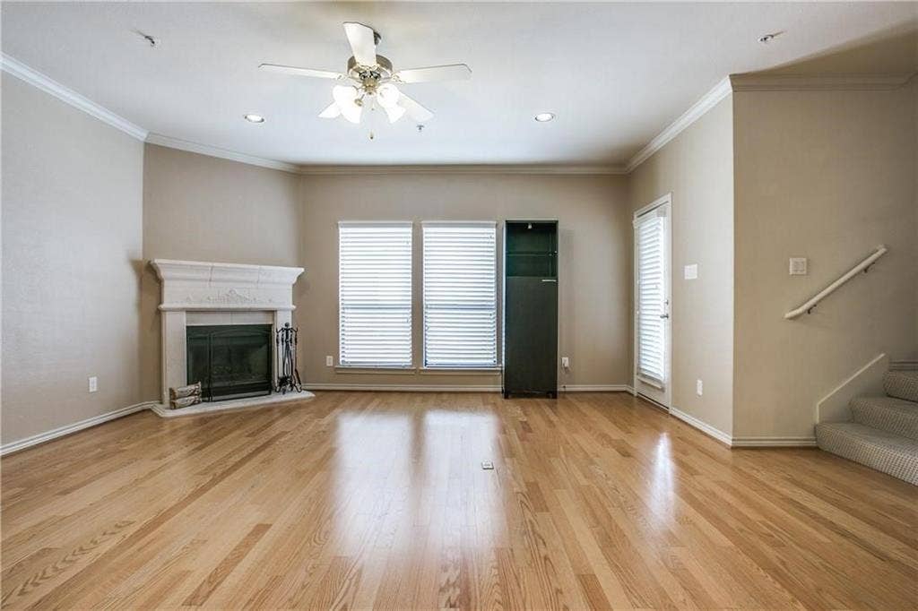 2415 Stutz Drive, #D, Dallas, TX 75235 Wood-finish flooring, crown molding, and a fireplace with a decorative mantel enhance the living space