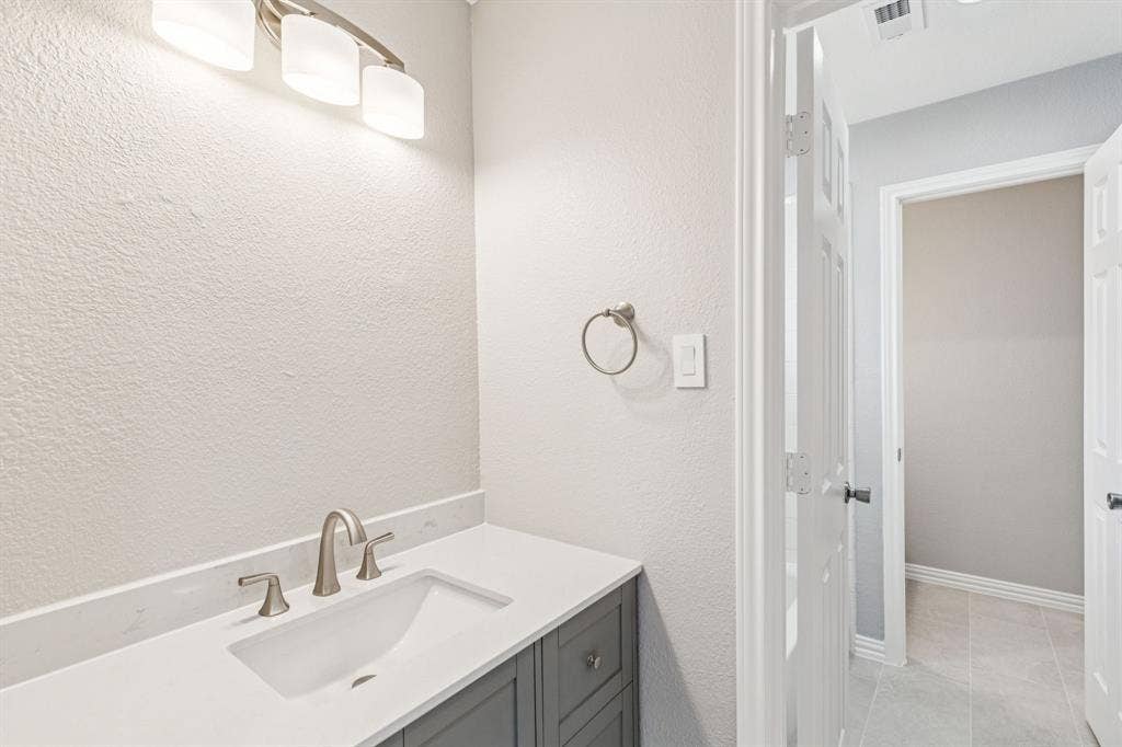 15456 Mountain View Lane, Frisco, TX 75035 Vanity with integrated sink and brushed nickel faucet, light-toned countertop, and gray cabinetry