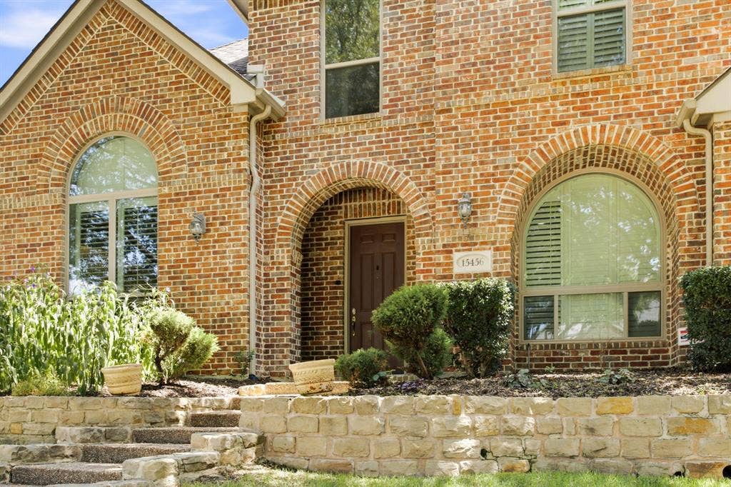 15456 Mountain View Lane, Frisco, TX 75035 Brick exterior with arched window details, stone retaining wall, and mature landscaping