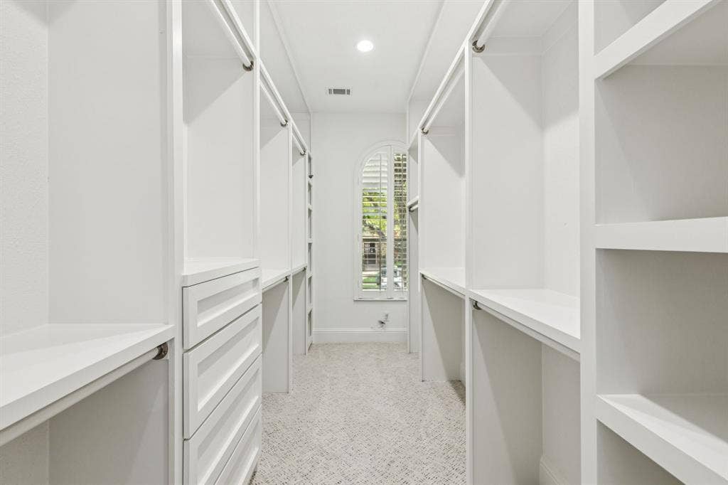 15456 Mountain View Lane, Frisco, TX 75035 Walk-in closet featuring built-in shelving, hanging rods, integrated drawers, and an arched window with plantation shutters