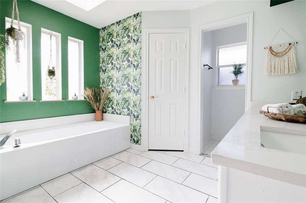 3612 Tumbril Lane, Plano, TX 75023 Soaking tub with a polished chrome fixture, white rectangular floor tiles, green accent wall, and a vanity with a white countertop