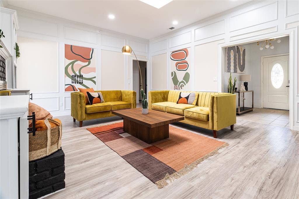 3612 Tumbril Lane, Plano, TX 75023 Light wood-finish flooring extending throughout, white paneled wall detailing, recessed lighting, and a white fireplace with a dark brick base