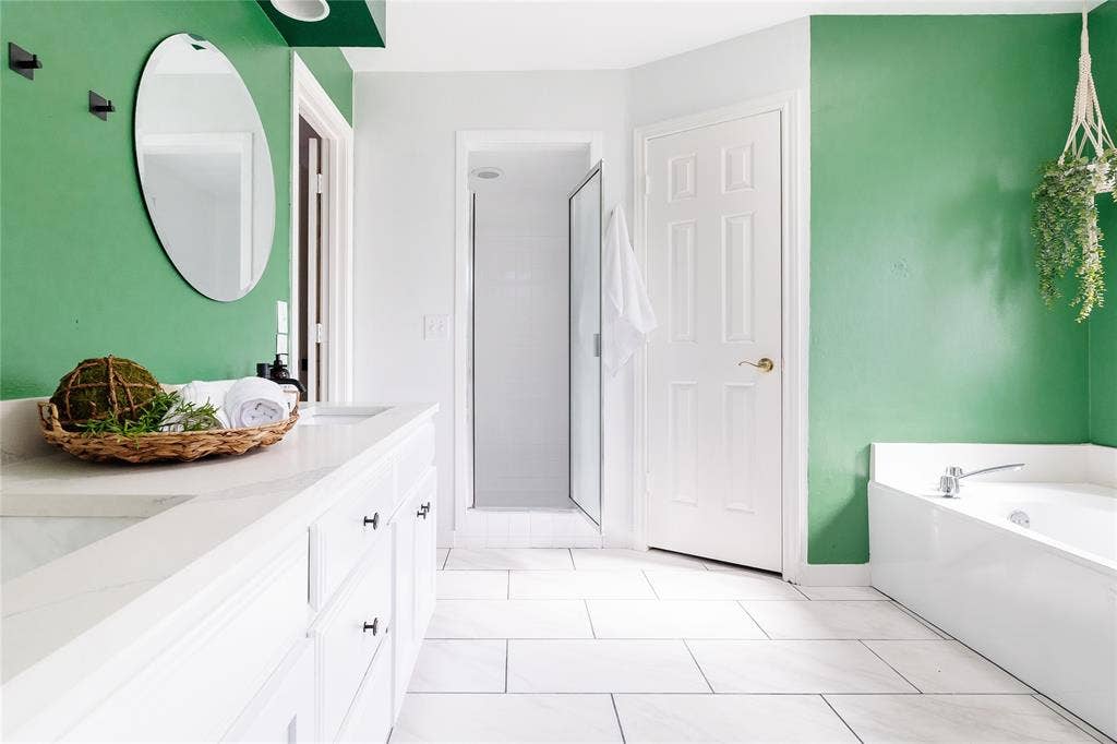 3612 Tumbril Lane, Plano, TX 75023 White tile flooring, spacious vanity with integrated sink, freestanding bathtub, and a glass-enclosed shower