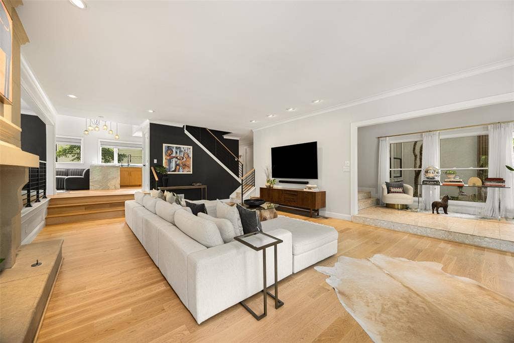 9863 Elmcrest Drive, Dallas, TX 75238 Expansive living area featuring light wood-finish flooring, recessed lighting, a stone fireplace surround, and a multi-level design.