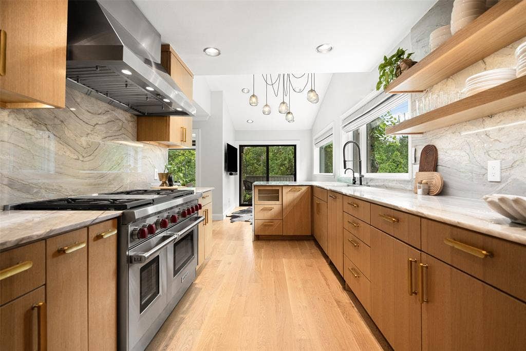 9863 Elmcrest Drive, Dallas, TX 75238 The thoughtfully designed kitchen features light wood-finishes, brass hardware, a Wolf stainless steel range, a built in Sub Zero refrigerator, and an abundance of storage.