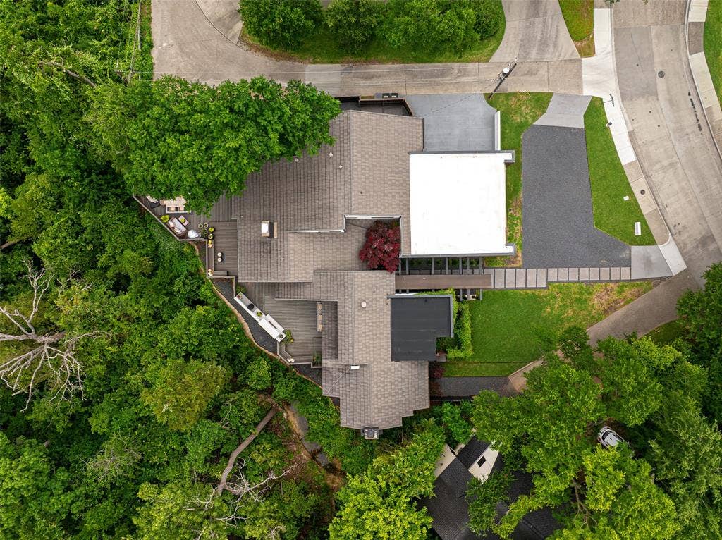 9863 Elmcrest Drive, Dallas, TX 75238 View of multi-level roof line with varied materials surrounded by mature trees and backing up to a creek.