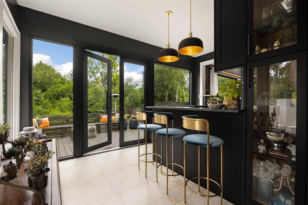 9863 Elmcrest Drive, Dallas, TX 75238 Custom wet bar has painted cabinetry with glass-front display storage and fluted paneling and oversized doors leading to patio.