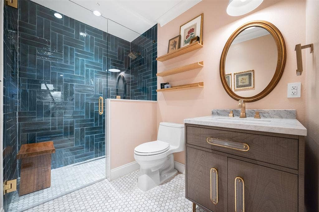 9863 Elmcrest Drive, Dallas, TX 75238 Gorgeous guest bathroom with a glass-enclosed shower, custom tile work, and pretty vanity with gold-toned fixtures.