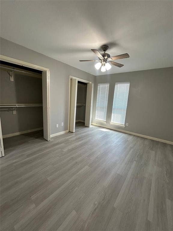 5826 Sandhurst Lane, #C, Dallas, TX 75206 Grey wood-finish flooring, two large windows with blinds, two open closet spaces, and a ceiling fan with integrated lighting