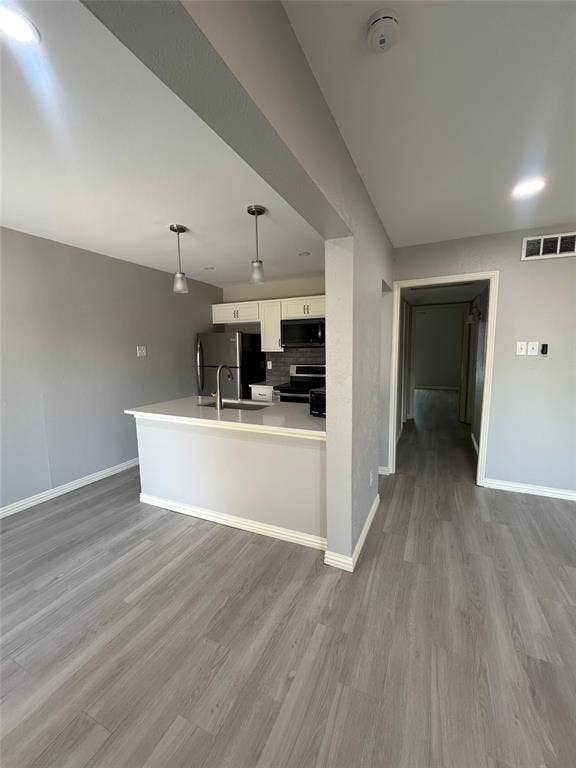 5826 Sandhurst Lane, #C, Dallas, TX 75206 Open-concept living area featuring wood-finish flooring, recessed lighting, and a kitchen with white cabinetry, stainless steel appliances, and a breakfast bar