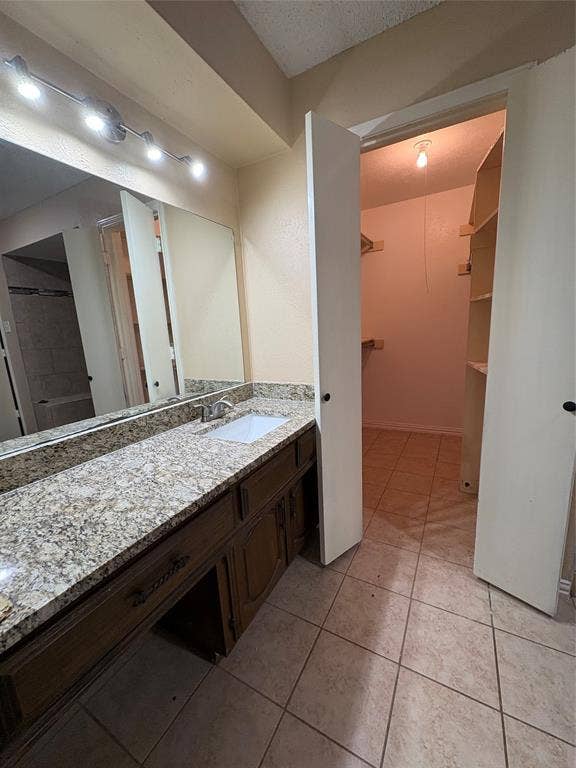1025 Cloverdale Lane, DeSoto, TX 75115 Spacious vanity with a granite countertop, undermount sink, and wood-finish cabinetry