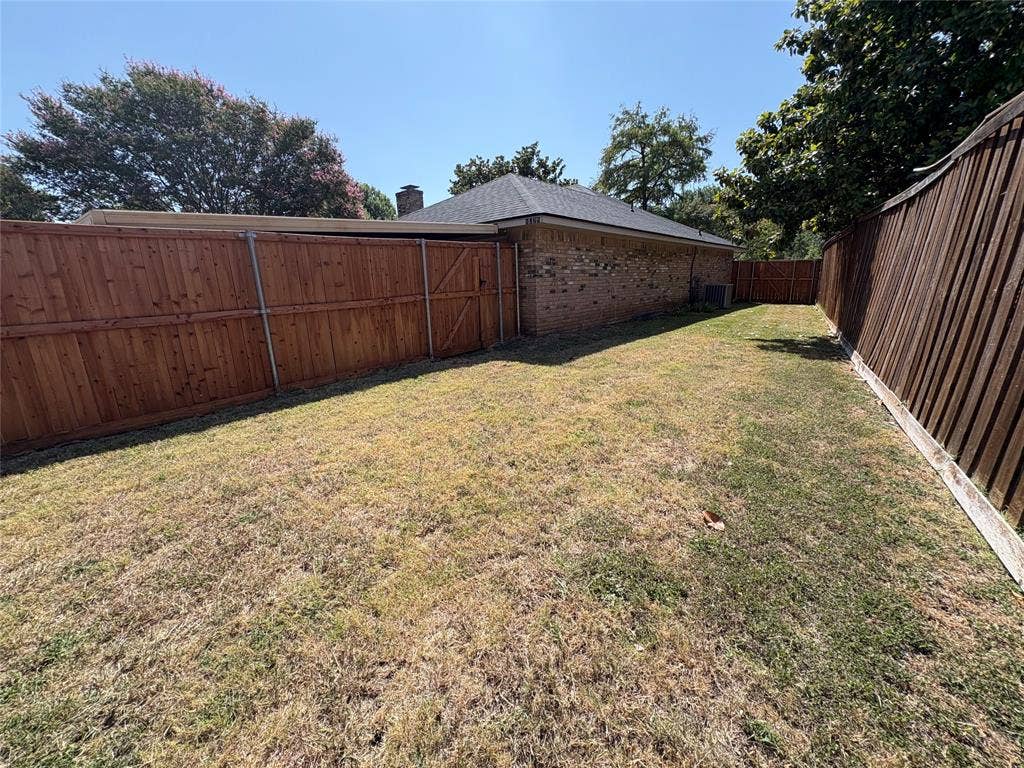 1025 Cloverdale Lane, DeSoto, TX 75115 Brick exterior with a dark-shingled roof, complemented by a wood fence, and mature trees