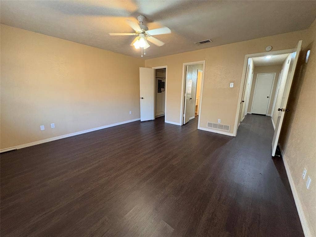 1025 Cloverdale Lane, DeSoto, TX 75115 Spacious room featuring wood-finish flooring, neutral-toned walls, and a ceiling fan