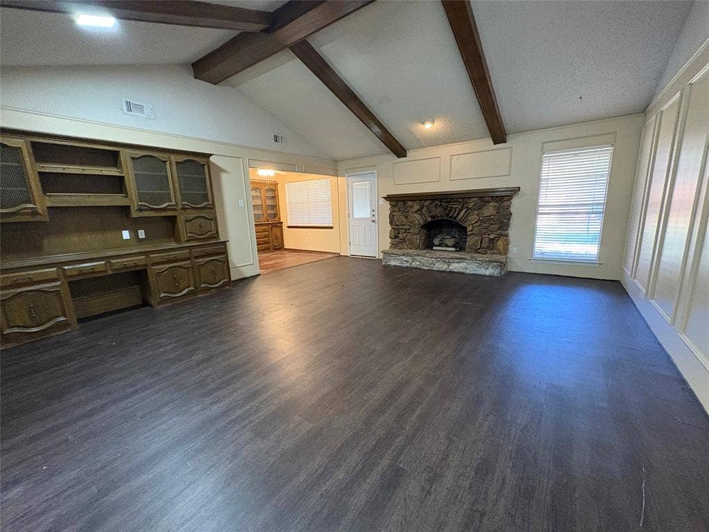 1025 Cloverdale Lane, DeSoto, TX 75115 Vaulted ceiling with exposed wood beams, stone fireplace, wood-finish flooring, built-in cabinetry, and panel molding