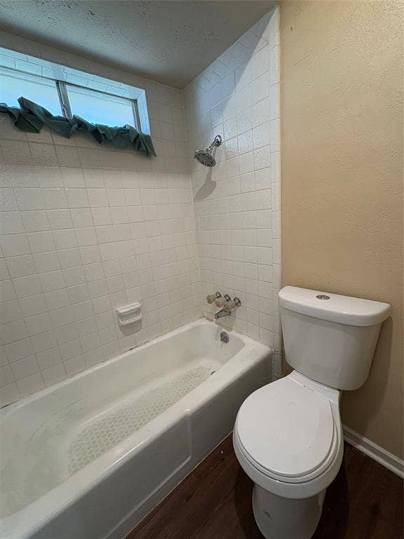 1025 Cloverdale Lane, DeSoto, TX 75115 White tiled shower surround, bathtub, toilet, and wood-finish flooring