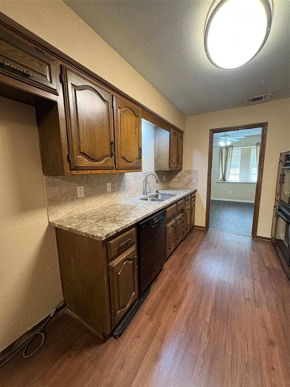 1025 Cloverdale Lane, DeSoto, TX 75115 Kitchen featuring wood-finish flooring, wood cabinetry, stone-finish countertops, a stainless steel sink with a gooseneck faucet, and a built-in dishwasher