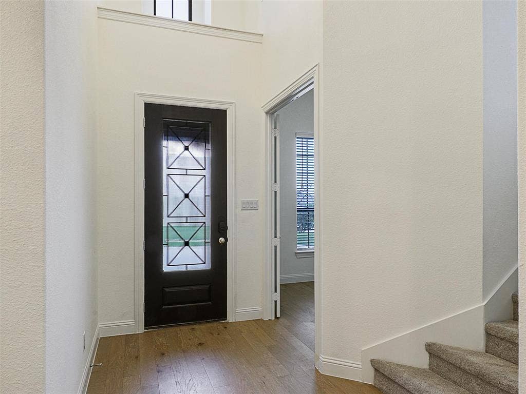 8305 Pine Island Way, McKinney, TX 75071 Dark entry door with decorative glass inserts, wood-finish flooring, and a carpeted staircase
