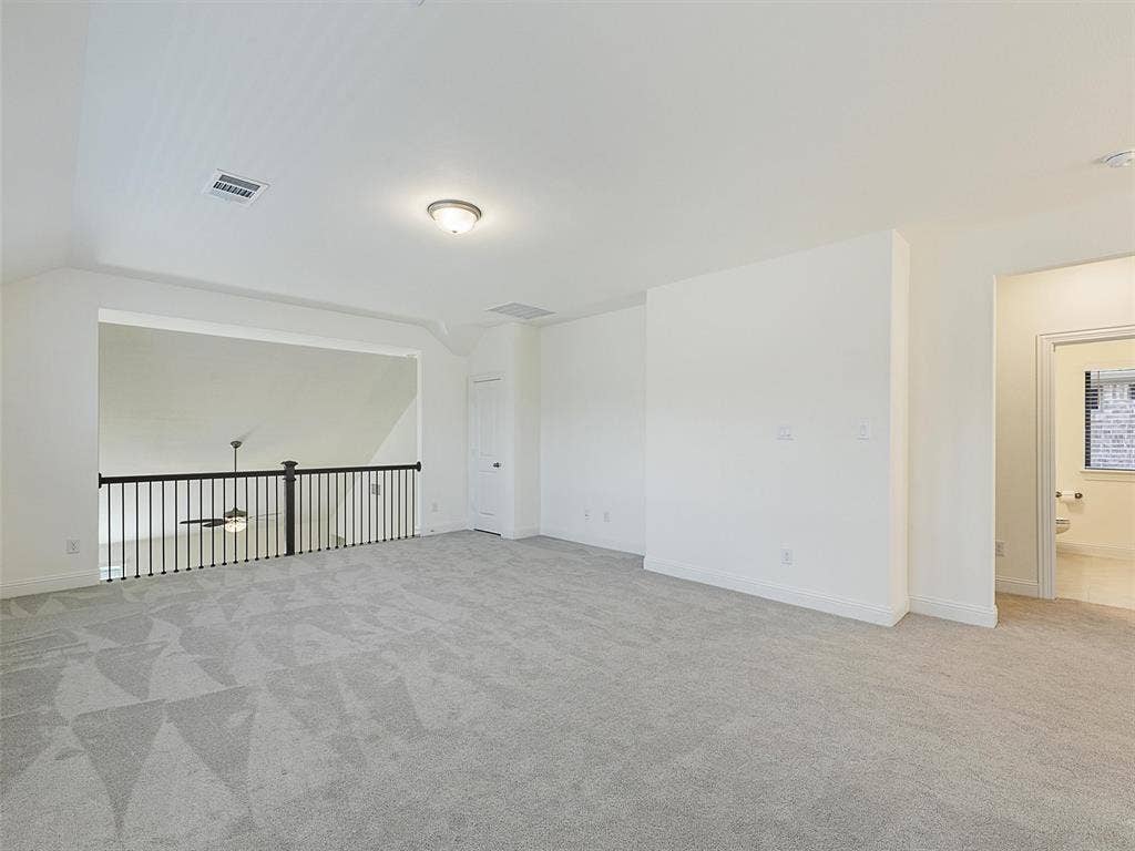 8305 Pine Island Way, McKinney, TX 75071 Expansive carpeted area with a white wall finish, an overhead flush mount light, and an open railing overlooking a lower level
