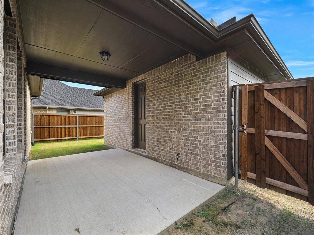 8305 Pine Island Way, McKinney, TX 75071 Covered concrete patio with a brick exterior, a wood privacy fence, and a dark-paneled door