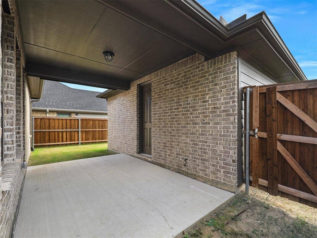 8305 Pine Island Way, McKinney, TX 75071 Covered concrete patio with brick exterior and dark wood fencing
