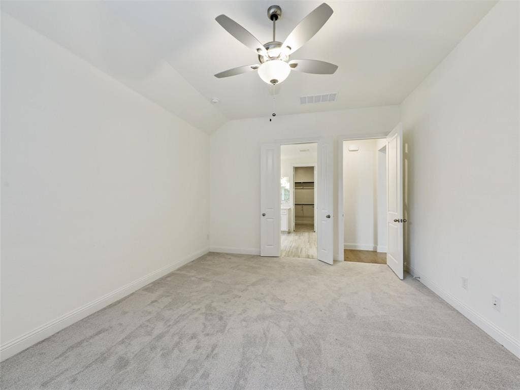 8305 Pine Island Way, McKinney, TX 75071 Spacious bedroom with neutral carpeting, ceiling fan with integrated lighting, and dual closet access