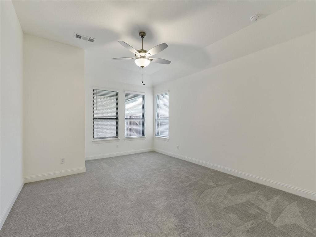 8305 Pine Island Way, McKinney, TX 75071 Carpeted room featuring multiple windows, a ceiling fan with integrated lighting, and neutral wall tones