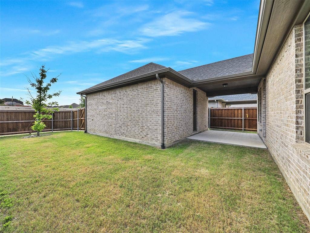 8305 Pine Island Way, McKinney, TX 75071 Expansive green lawn, a covered patio, brick exterior, and a wood privacy fence