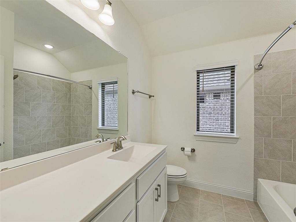 8305 Pine Island Way, McKinney, TX 75071 Vanity with a single sink and white cabinetry, a large wall-mounted mirror, a tiled shower/tub combination, tiled flooring, and a window with blinds