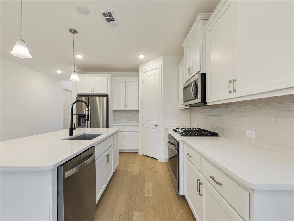 8305 Pine Island Way, McKinney, TX 75071 Kitchen with white cabinetry, stainless steel appliances, a center island with a sink, and wood-finish flooring