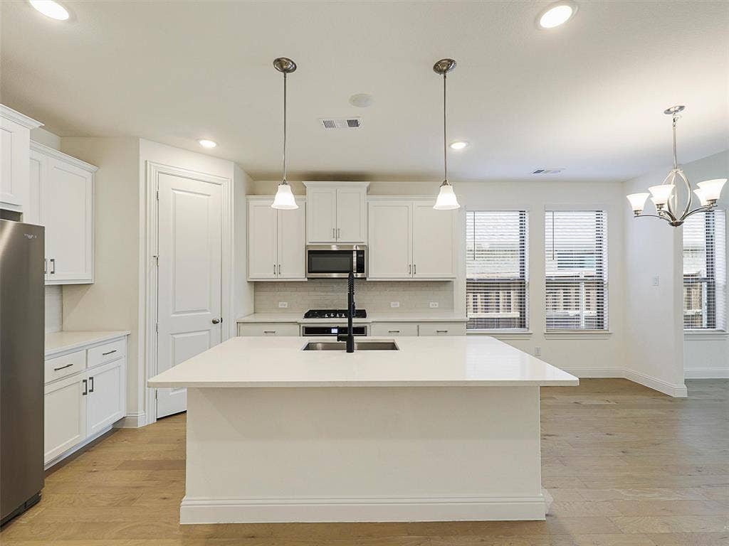 8305 Pine Island Way, McKinney, TX 75071 Kitchen with white cabinetry, stainless steel appliances, a center island with sink, and wood-finish flooring