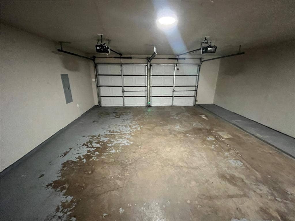 Two-car garage featuring automatic door openers, a wall-mounted electrical panel, and an overhead light fixture