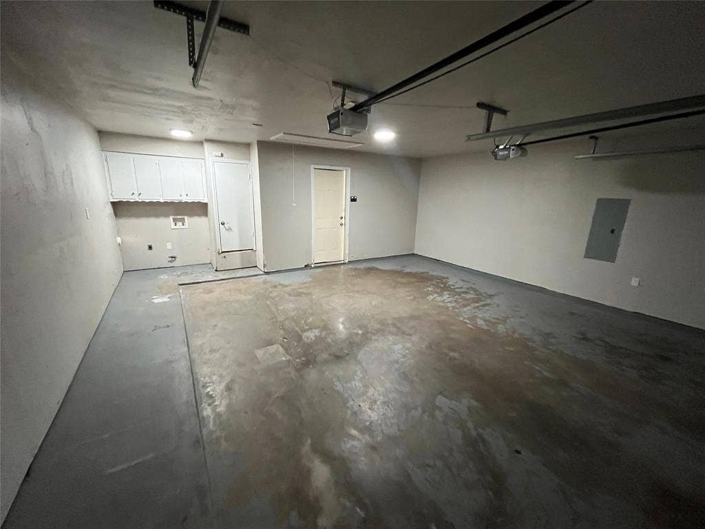 Attached garage featuring overhead lighting, multiple garage door openers, and built-in cabinetry