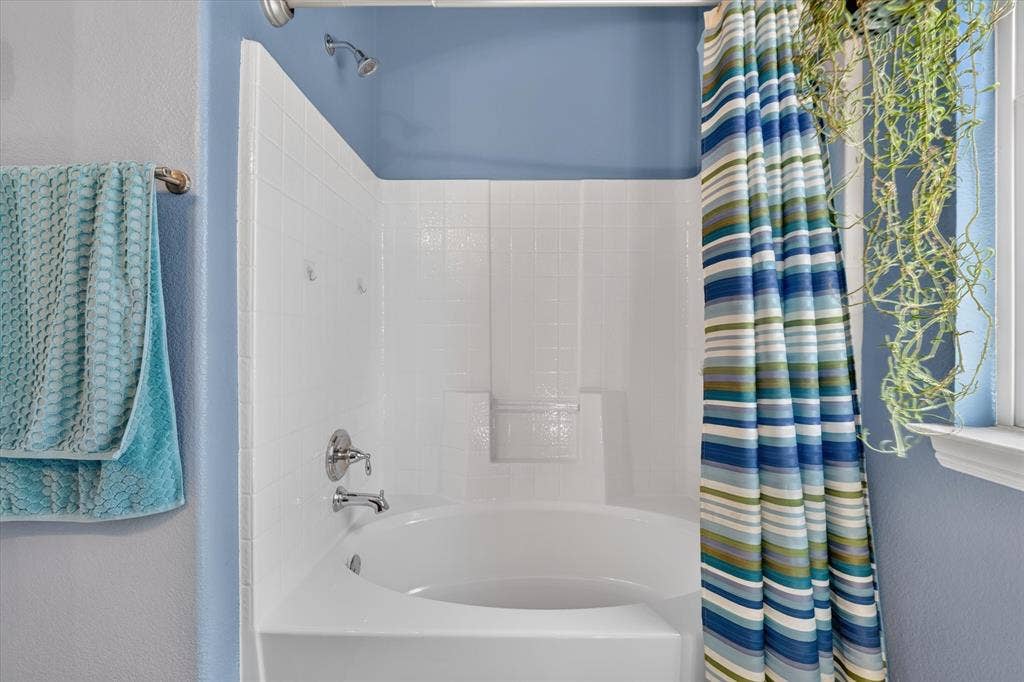 424 Foxcraft Drive, Fort Worth, TX 76131 White tiled shower/tub combination with chrome fixtures