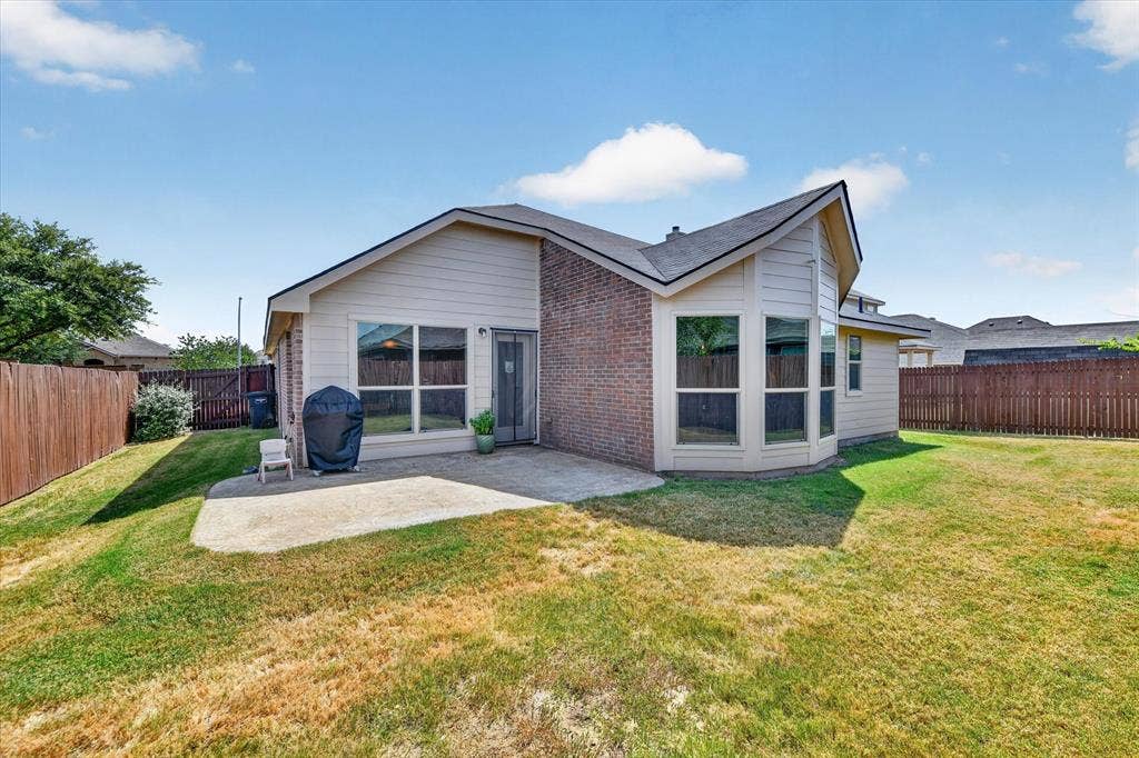 424 Foxcraft Drive, Fort Worth, TX 76131 Rear exterior with a concrete patio, brick and siding facade, multiple large windows, and a fenced backyard