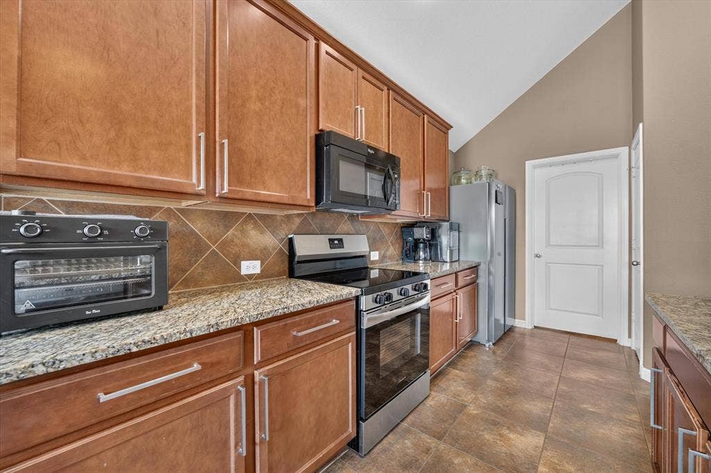 424 Foxcraft Drive, Fort Worth, TX 76131 Vaulted ceiling, wood cabinetry, granite countertops, tile backsplash, and stainless steel appliances