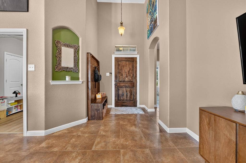 424 Foxcraft Drive, Fort Worth, TX 76131 Tiled flooring, arched doorway, recessed wall niche, natural wood-finish door, pendant light fixture