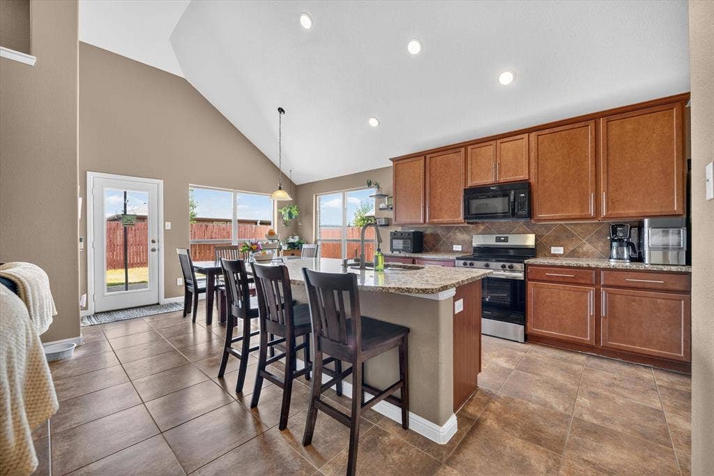 424 Foxcraft Drive, Fort Worth, TX 76131 Kitchen featuring a large island, wood-finish cabinetry, tile flooring, and vaulted ceiling