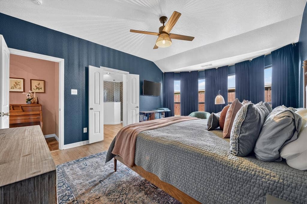 424 Foxcraft Drive, Fort Worth, TX 76131 Vaulted ceiling with wood-finish ceiling fan, light wood-finish flooring, and multiple windows with full-length drapery