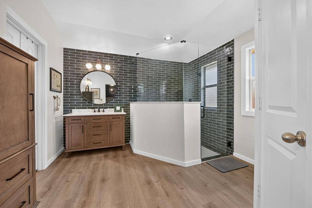424 Foxcraft Drive, Fort Worth, TX 76131 Wood-finish flooring with a wood vanity, white countertop, and dark subway tile accent wall