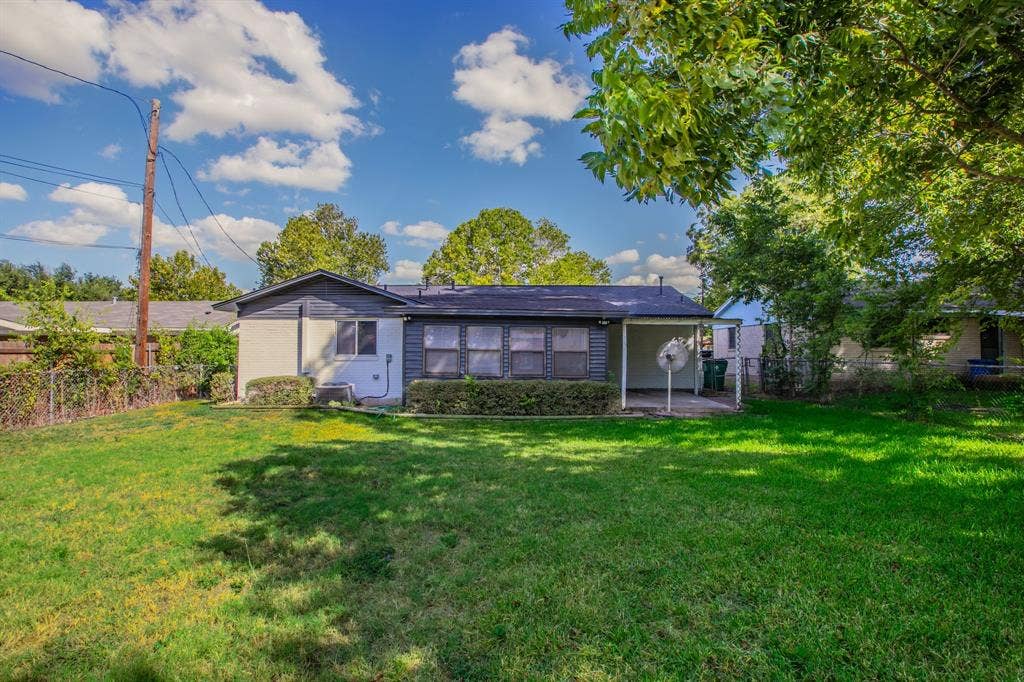 4133 Sherry Lane, Beverly Hills, TX 76711 Expansive rear yard with a covered patio, mature landscaping, and a low-maintenance chain link fence