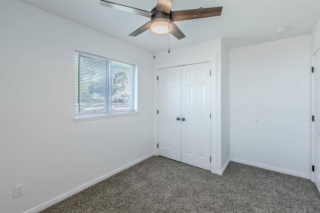 4133 Sherry Lane, Beverly Hills, TX 76711 Textured carpeting, a ceiling fan with light fixture, double panel closet doors, and a window with blinds