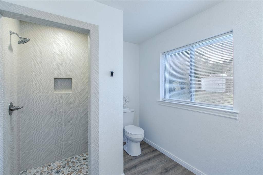 4133 Sherry Lane, Beverly Hills, TX 76711 Walk-in shower with chevron-patterned tile, integrated niche, and pebble-finish flooring