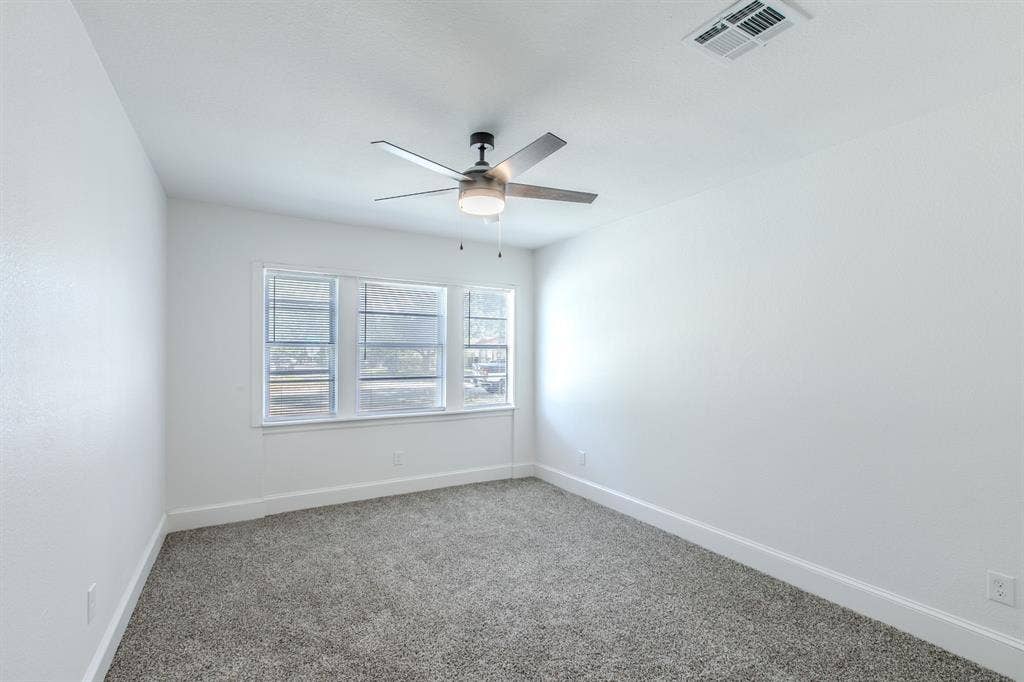 4133 Sherry Lane, Beverly Hills, TX 76711 Light gray carpeting, white walls, multiple windows, overhead ceiling fan with lighting, white trim