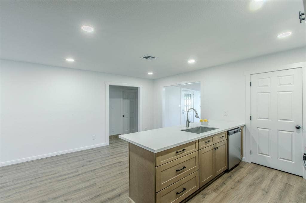 4133 Sherry Lane, Beverly Hills, TX 76711 Kitchen island with light wood-finish cabinetry, stainless steel sink, and light-toned countertop